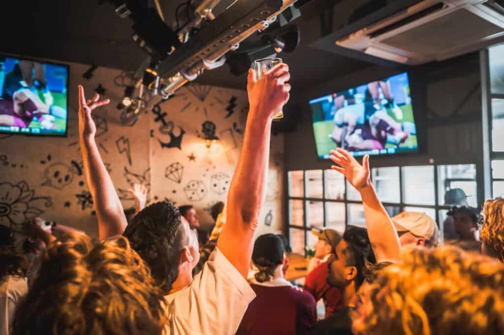 Lively group of young people enjoying drinks and watching sports at St Christopher’s Berlin Mitte Ho.