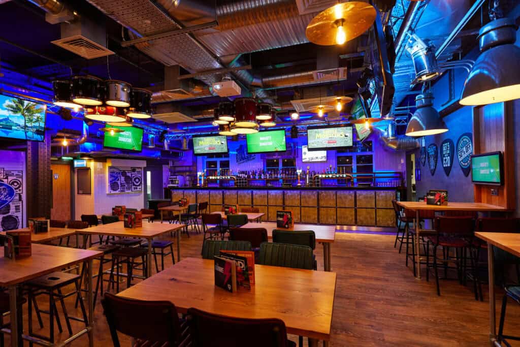 Brightly lit sports bar with TVs, tables, and bar counter in Berlin.