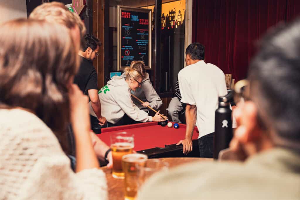 Group of young people playing pool at St Christopher’s Berlin Mitte Hostel bar.
