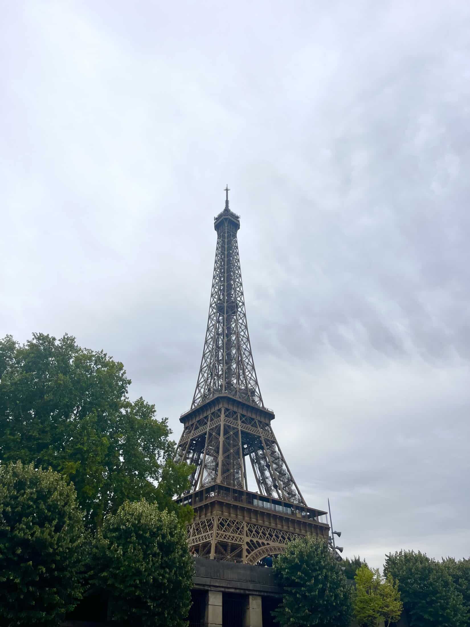 Eiffel Tower replica visible from Mitte Hostel in Berlin, with trees and cloudy sky in the backgroun.
