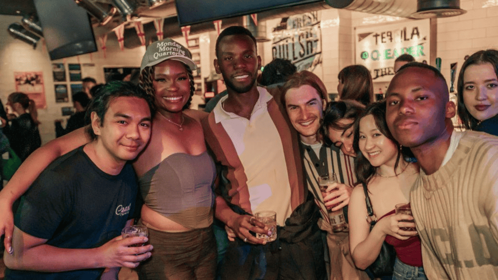 Group of diverse young adults enjoying drinks at Mitte Hostel, Berlin’s vibrant social hub.