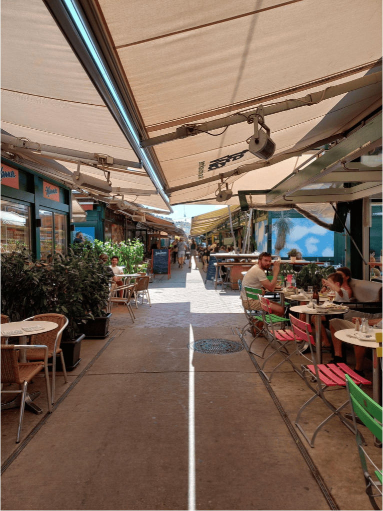 Outdoor terrace with colourful seating and umbrellas at St Christopher’s Berlin - Mitte.