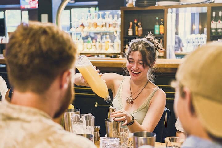 Lively scene at Mitte Hostel bar with smiling guests enjoying drinks in Berlin.