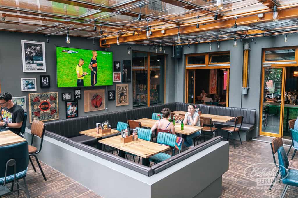 Bright hostel lounge with colourful chairs, wall art, and large TV in Berlin.