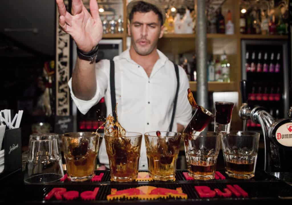 Young man serving drinks at Mitte Hostel bar in Berlin, lively nightlife scene.