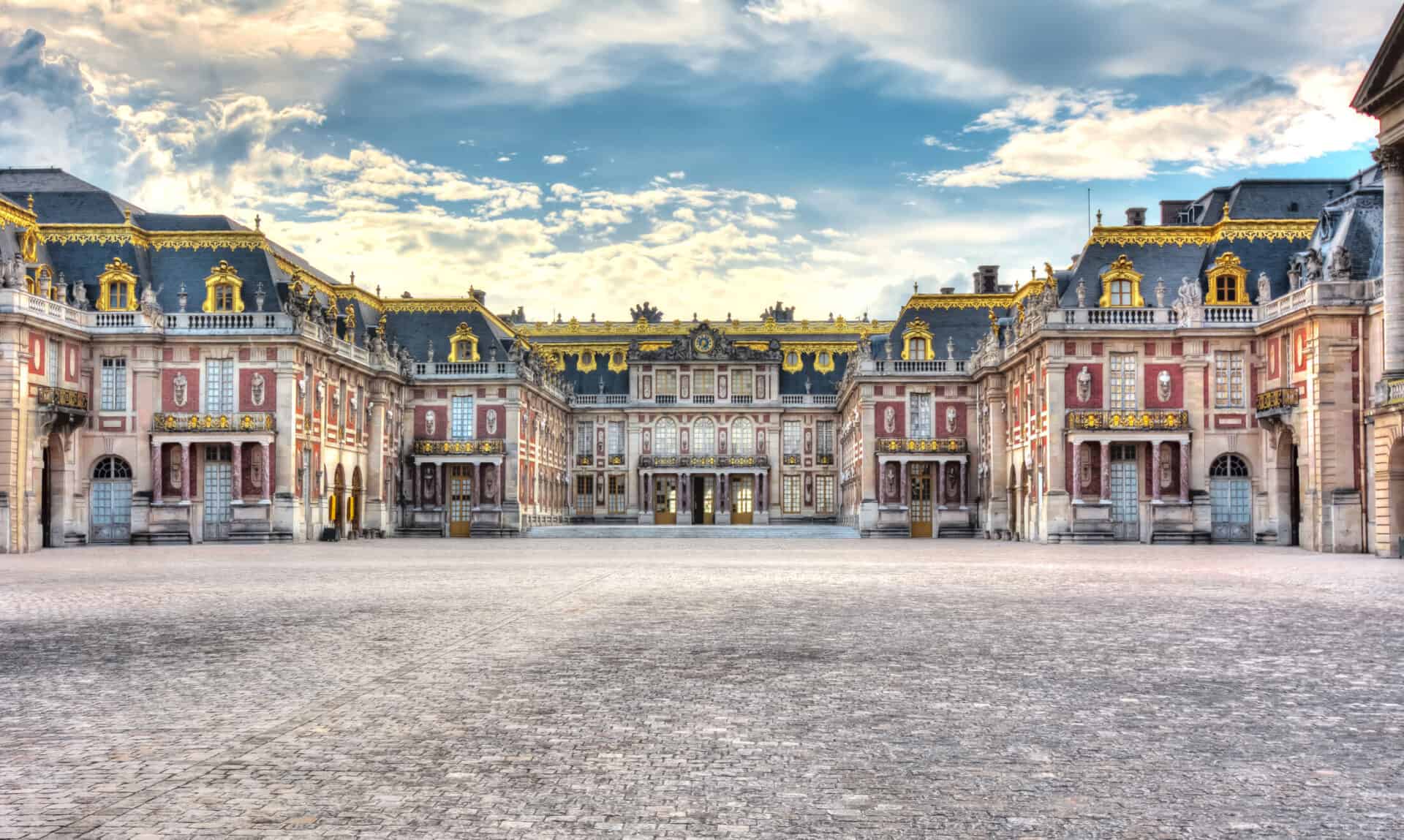 View of the Palace of Versailles with ornate architecture and expansive courtyard in France.