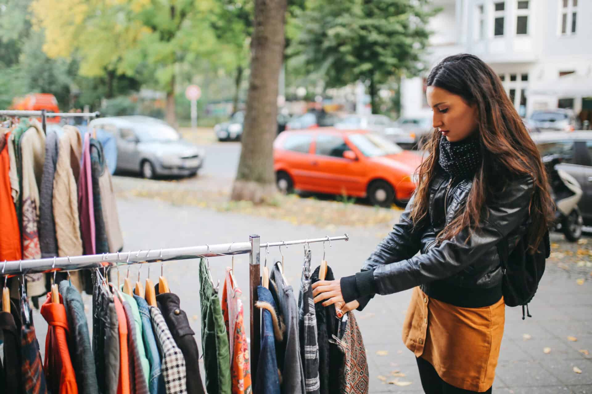 Young woman browsing clothing rack at outdoor market in Berlin.