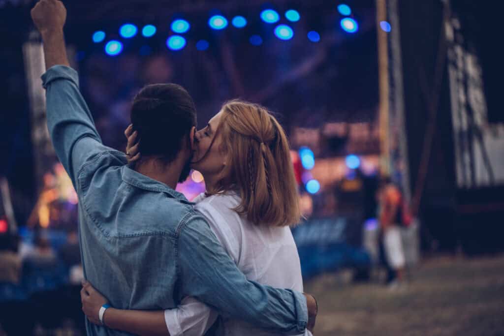 Young couple kissing at outdoor music festival in Berlin Mitte area.