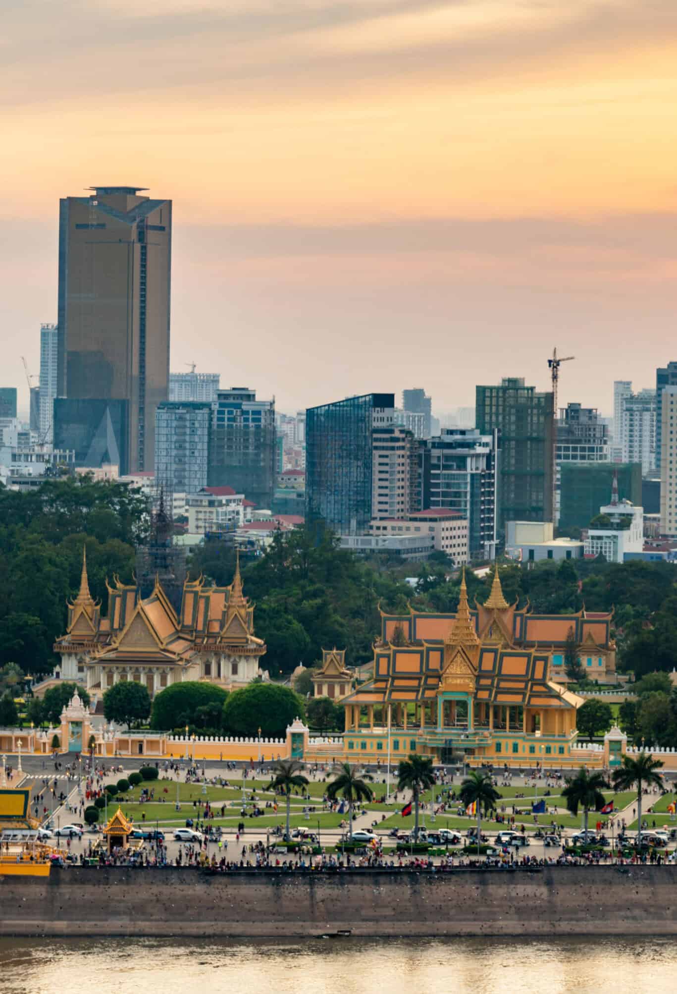 View of historic St Christopher's temple with modern Bangkok skyline at sunset.