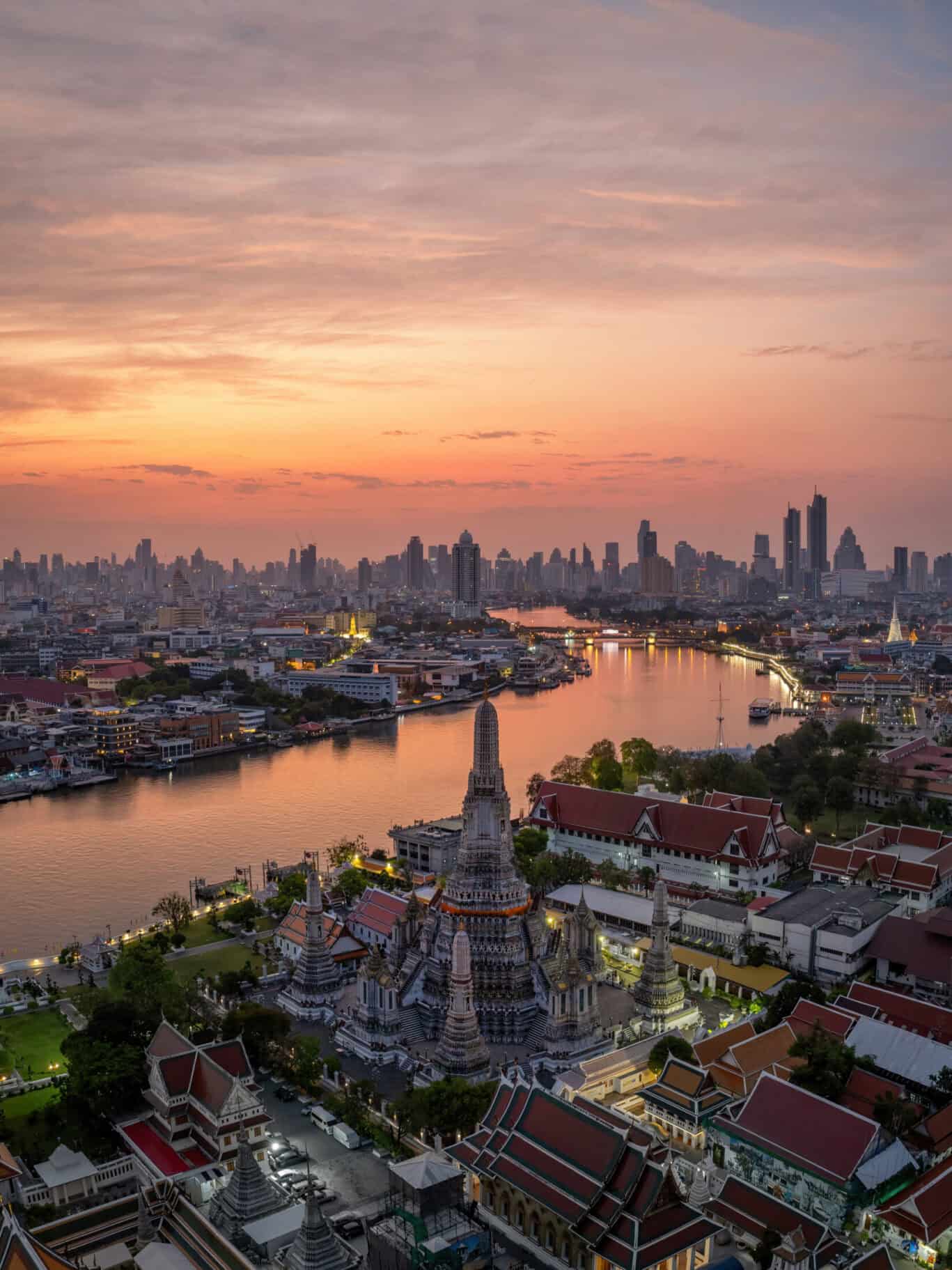 Bangkok skyline at sunset with historic temples and modern skyscrapers.