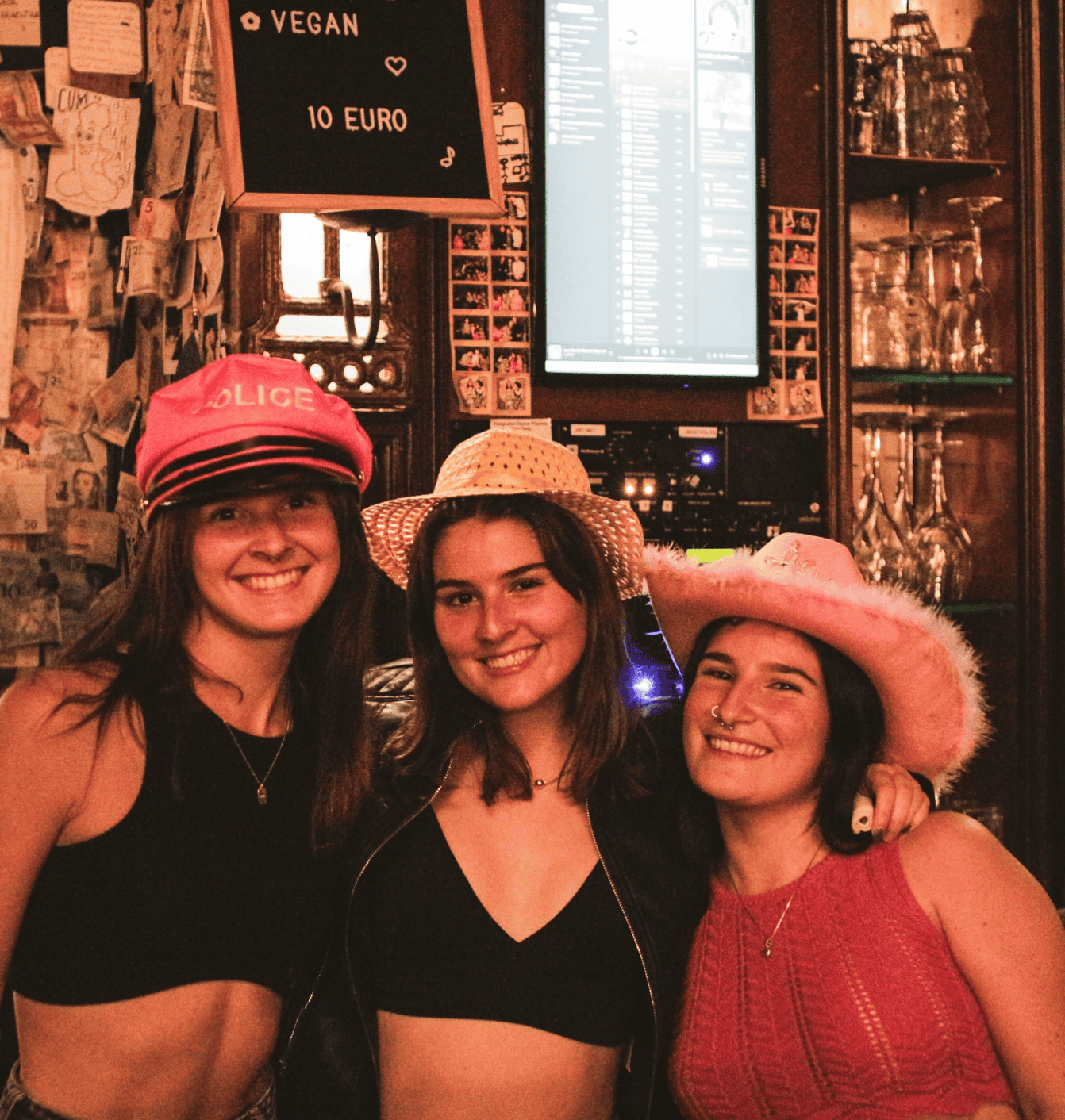 Group of three women wearing playful hats at St Christopher's pub, enjoying a night out.