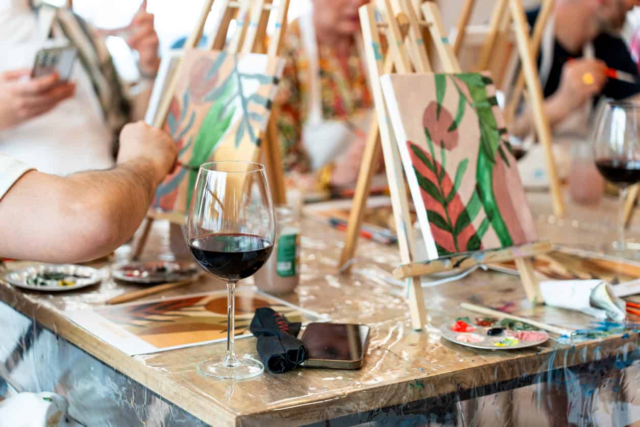 Painting workshop at St Christopher's featuring artists, canvases, and wine glasses.