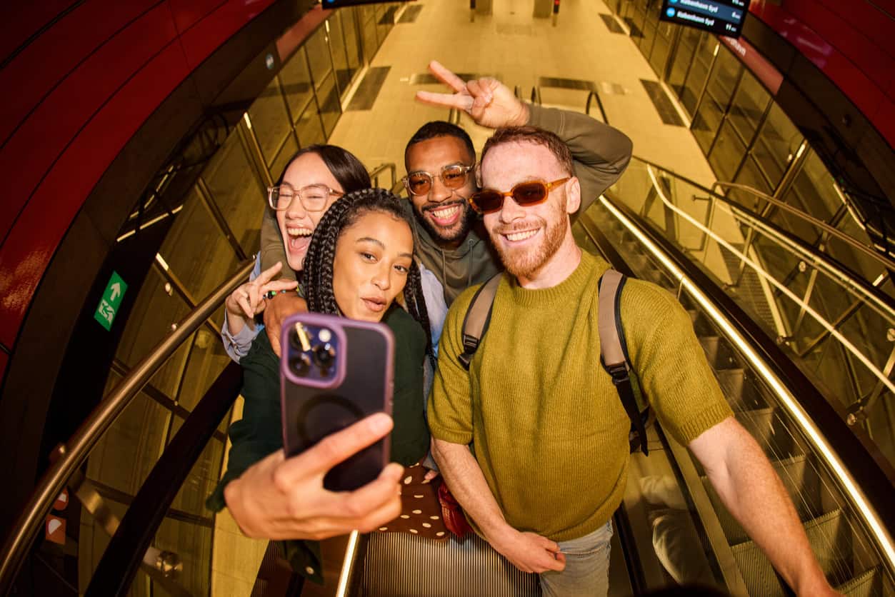 Diverse group of friends taking a selfie at airport terminal.