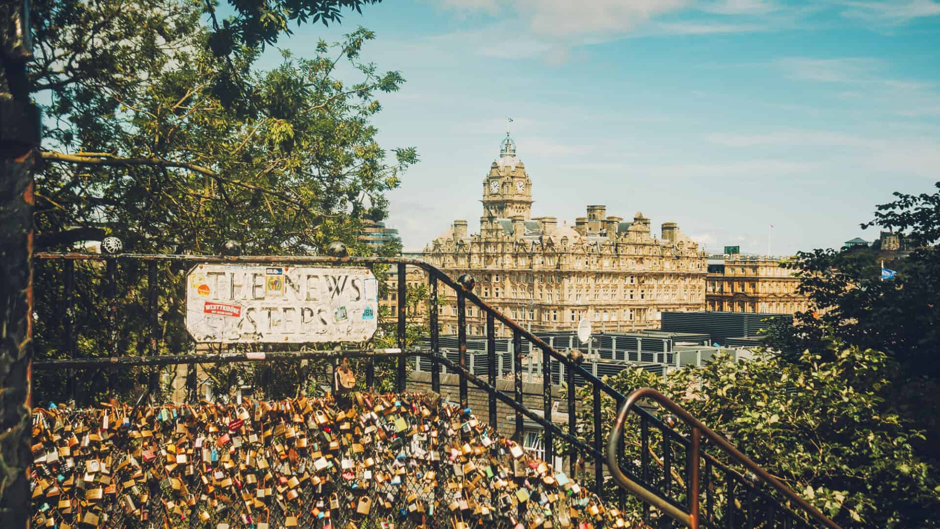 View of St Christopher's Church with city skyline and locks on bridge railing.